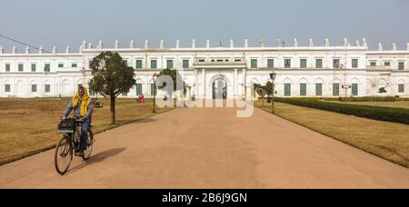 Murshidabad, Westbengalen/Indien - Januar 15 2018: Ein Mann auf dem Fahrrad fährt auf der breiten Straße, die zum Nizamat Imambara führt. Stockfoto