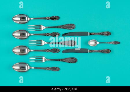 Besteck, Gabeln, Löffel und Messer auf blauem Hintergrund, flach liegend oder Draufsicht. Stockfoto