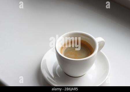 Frisch gebrühter Kaffee in der Demitasse Tasse von Espresso Machine. Tasse Kaffee an der Theke. Stockfoto