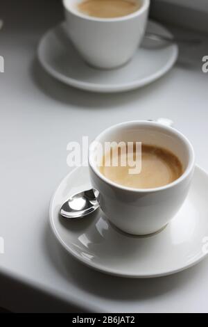 Frisch gebrühter Kaffee in der Demitasse Tasse von Espresso Machine. Tassen Kaffee an einer Bar-Theke. Kaffeepause. Stockfoto