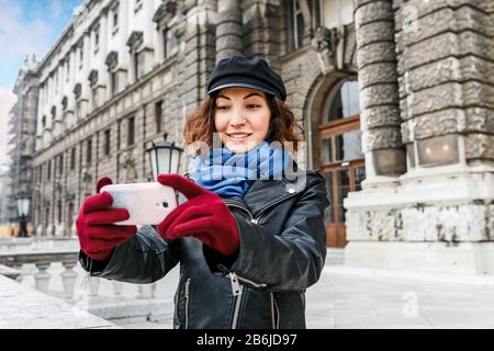 Portrait des süßen Mädchens in Lederjacke macht selfie auf dem Smartphone auf der Straße in der europäischen Altstadt Stockfoto