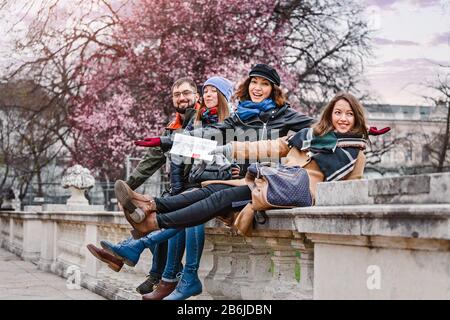 Eine multirassische Gruppe junger Menschen, die sich in einem Frühlingspark gegen eine blühende Kirschblüte lustig machen Stockfoto