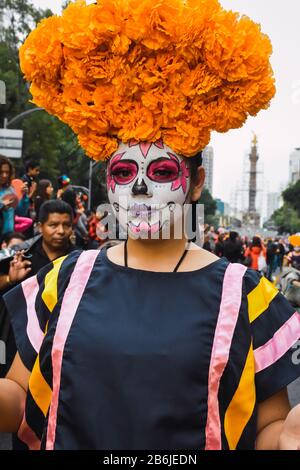 Mexiko-Stadt, Mexiko,; 26. Oktober 2019: Schöne Frau als catrina gekleidet mit Blumenschmuck auf dem Kopf in der Prozession der Katrinen in mexiko Stockfoto