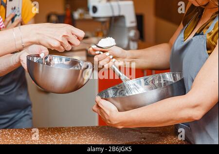 Zwei Frauen Freunden sich eine Schürzen an, die in der Schüssel Mehl kochen Stockfoto