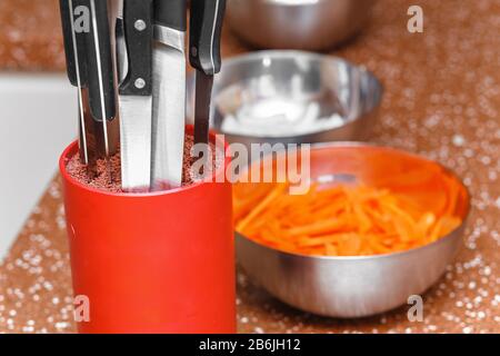 Satz Küchenmesser im Ständer am Hintergrund des Gemüses Stockfoto