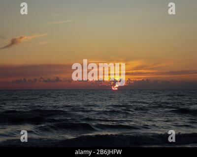 Wunderschöner oranger Sonnenuntergang auf dem Meer mit Wellen Stockfoto