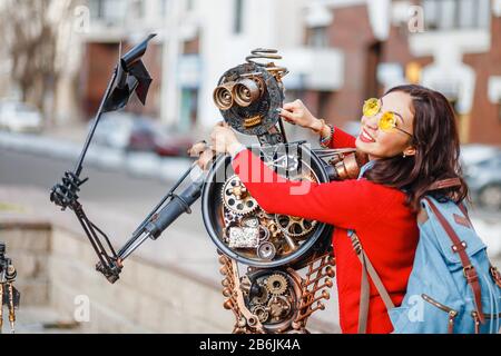 28. APRIL 2018, UFA, RUSSLAND: Frau berührt Roboterstatue, die aus Müll und Metallabfällen auf der Straße der Stadt Ufa entstanden ist Stockfoto