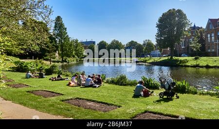 Stadt Leiden, Provinzland Südholland, Niederlande, Europa - im botanischen Garten entspannen sich die Menschen am Kanal Moresigel, der Hortus botanicus Leiden ist der älteste botanische Garten der Niederlande. Der Clusius-Garten gibt einen Impressioof dessen, was der Hortus um 1600 war, dem ältesten Sektioof des Hortus, der auf das Jahr 1590 zurückgeht, und der Citof Leiden ist bekannt für seine säkulare Architektur, seine Kanäle, seine Universitof 1590, die nativitof Rembrand, Die Stadt, in der die erste Tulpe Europas im 16. Jahrhundert geblüht wurde Stockfoto