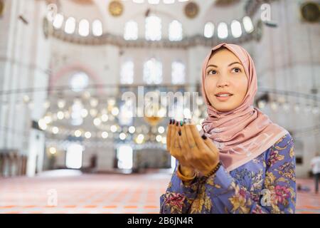 Junge hübsche muslimische Frau, die in der Moschee betet Stockfoto