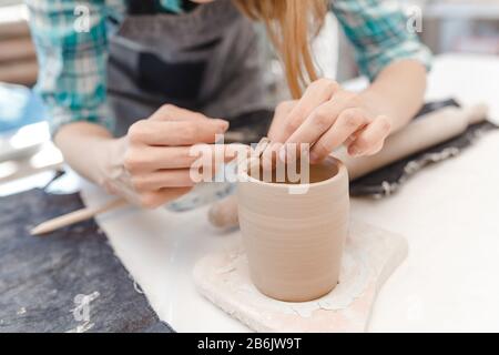 Nahaufnahme eines Töpfers, der Tongeschirr in einer Werkstatt mit verschiedenen Werkzeugen anstellt und formt Stockfoto