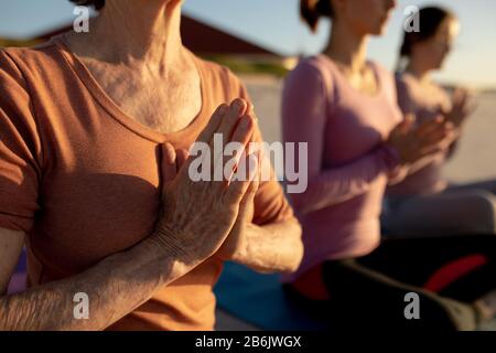 Nahaufnahme der Frauen, die am Strand Yoga machen Stockfoto