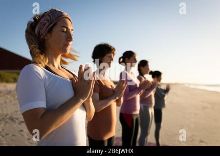 Seitenansicht der Frauen, die am Strand Yoga machen Stockfoto