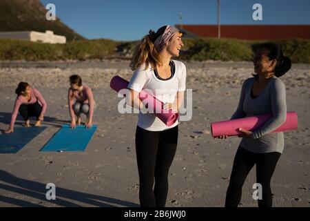 Vorderansicht der Yoga-Frauen, die am Strand diskutieren Stockfoto