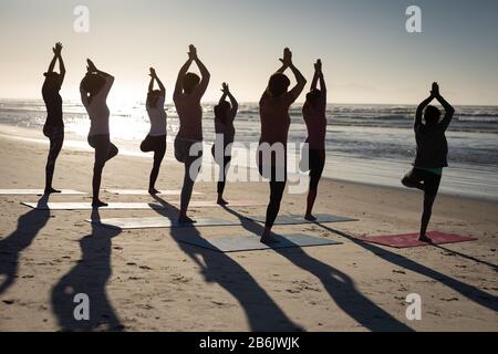 Rückansicht der Frauen, die am Strand Yoga machen Stockfoto