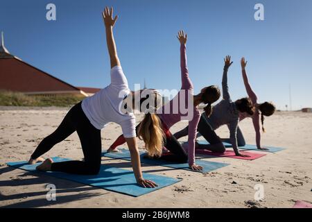 Rückansicht der Frauen, die am Strand Yoga machen Stockfoto
