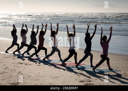 Rückansicht der Frauen, die Yoga-Positionen am Strand einnehmen Stockfoto