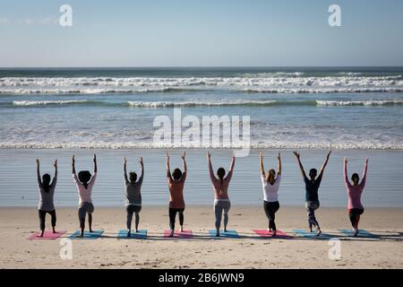 Rückansicht der Frauen, die am Strand Yoga machen Stockfoto