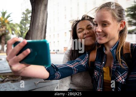 Seitenansicht von Freunden, die Selfies auf der Straße nehmen Stockfoto