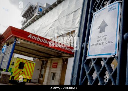 Ein NHS-Schild weist auf einen Testpod von Coronavirus hin, da ein Krankenwagen am 11. März 2020 in London, England, in der A&E-Abteilung des Kings College Hospital in Camberwell im Süden Londons eintrifft. Stockfoto