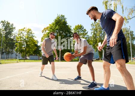 Sport, Freizeit Spiele und männliche Freundschaft Konzept - Gruppe der Männer oder Freunde spielen street Basketball Stockfoto