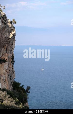 Hohe imprägnierbare Klippe mit schlechter Bergvegetation auf der Oberseite und ruhigem Meer weit und unten und türkisches Antalya Stadt auf Skyline Blick am sonnigen Tag Stockfoto