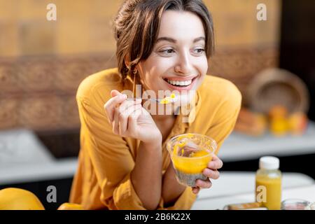 Portrait einer jungen und fröhlichen Frau, die chia Pudding isst, einen Snack oder ein Frühstück in der Küche hat. Konzept der Ernährung, gesunden Ernährung und Wellness Stockfoto