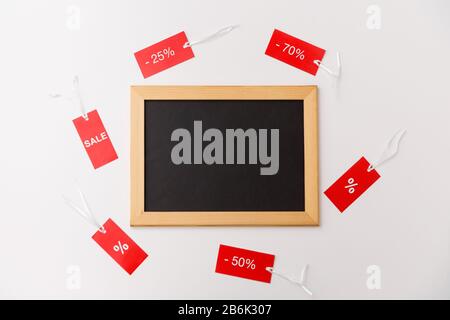 Einkaufs-, Verkaufs- und Marketingkonzept - schwarze Kreidetafel und rote Schilder mit Rabattzeichen auf weißem Hintergrund Stockfoto