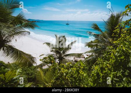 Urlaub im Petite Anse Paradise Beach, umrahmt von grünem Laub. Insel La Digue, Seychellen. Stockfoto