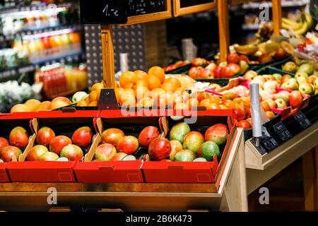 Verschiedene Früchte in Kisten auf dem Markt im Innenbereich - Mango, Orangen, Äpfel Stockfoto