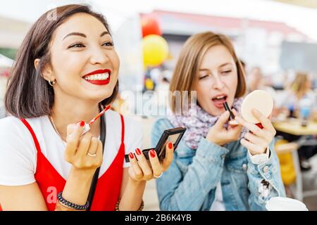 Zwei Mädchen Freundin zog sich Make-up, Lippenstift und Blick in den Spiegel. Das Konzept von Kosmetik- und Lifestyle-Beziehungen Stockfoto