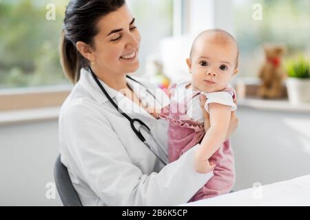 Konzept für Medizin, Gesundheitswesen und Pädiatrie - lächelnde weibliche Kinderärztin oder Krankenschwester, die eine Patientin in der Klinik oder im Krankenhaus hält Stockfoto