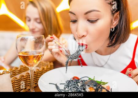 Frau, die Delikatesse schwarze Pasta mit Tintenfisch isst Stockfoto