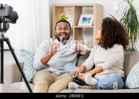 Blogging, Videoblog und People Concept - glückliches afroamerikanisches Paar Videoblogger mit Videoblogging zu Hause Stockfoto
