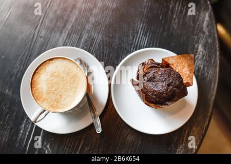 Kaffee mit Schokoladenmuffin auf altem Holztisch im Café. Draufsicht Stockfoto