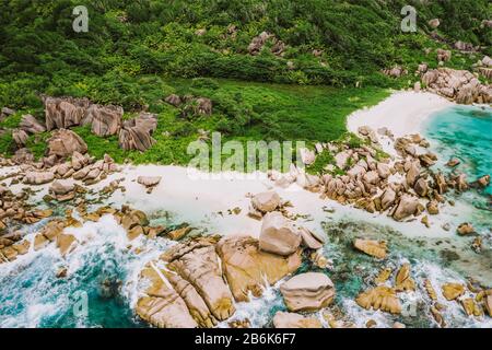 Luftdrone auf der Insel La Digue vom tropischen Geheimstrand Marron der Seychellen erschossen. Weißer Sandstrand mit türkisfarbenem Meerwasser und orangefarbenem Granit Stockfoto