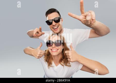 Glückliches Paar in Sonnenbrille, das Frieden zeigt Stockfoto