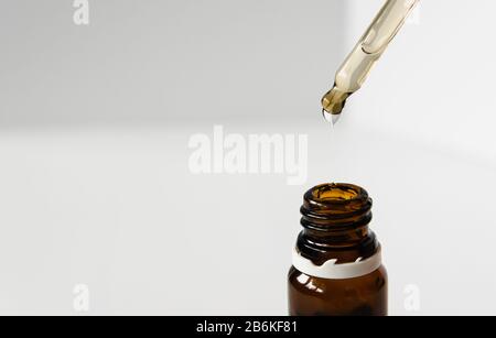 Kosmetik, Hyaluronsäure fließt von einer Pipette in eine Glasflasche auf weißem Grund Stockfoto