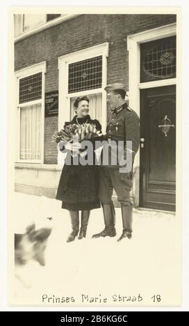 Deutscher Soldat mit Holländerin im Schnee EIN deutscher Soldat steht lächelnd neben einer Holländerin im Schnee. Sie hält einen großen Haufen Tulpen in den Armen und lächelt ihn an. Hinter ihnen hat man mit Buntglasfenstern Häuser und ein Zeichen für eine Firma hinterlassen. Ein Gast? Den Kopf eines Hundes verlassen. Unter dem Foto Princess Marie Street 18. (Gleicher Typ wie NG 2007-5-35 t/m 45). Hersteller : Fotograf: Anonymer Ort Herstellung: Den Haag Datum: Mai 1940 - 1943 Physische Merkmale: Gelatine silberfarbenes Druckmaterial: Papiertechnik: Gelatine silberfarbenes Druckmaß: H 11 cm. B × 6,5 cm. Betreff: OC Stockfoto