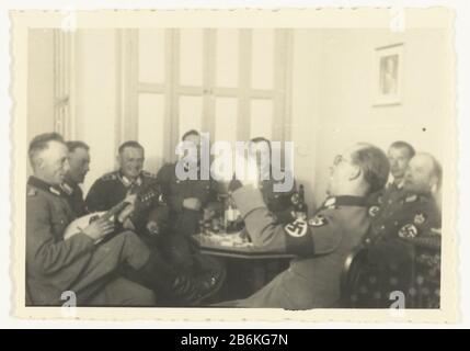 Deutsche Soldaten feiern EINE Gruppe von Wehrmachtssoldaten (Arbeitsabteilung) feiern und singen. Einer von ihnen spielt eine Mandoline. Auf dem Tisch und trinken Sie eine Kerze in einer Flasche. An der Wand eines Porträts A. Hitler. Hersteller : Fotograf: Anonymer Standort Herstellung: Niederlande Datum: 1941 - 1942 Physische Eigenschaften: Gelatine silberfarbenes Druckmaterial: Fotopapier Technik: Gelatine silberner Druck Abmessungen: H 5,5 cm. B × 8,5 cm. Betrifft: Besetzung   Oorlogerholung der Soldat aus dem Dienst Krieg II Besetzung der Niederlande, Wenn: 1941 - 1942 Stockfoto