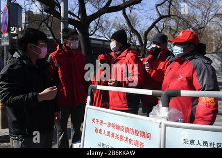 (200311) -- PEKING, 11. März 2020 (Xinhua) -- der Gemeinschaftsarbeiter Su Tianxiang (3. R) stellt Bewohner vor, die gerade nach Peking zurückgekehrt sind, wie man persönliche Informationen in Xiaojingchang Hutong im Distrikt Dongcheng in Peking, der Hauptstadt Chinas, am 10. März 2020 registriert. Die Hutongs in Peking, dem meist geschäftigen Labyrinth traditioneller Gassen, wurden nach dem Ausbruch der neuartigen Coronavirus-Krankheit, kurz COVID-19, in China deutlich leiser. Seitdem bemühen sich die Gemeindearbeiter, das Sicherheitspersonal und die Freiwilligen, die Bedürfnisse der Anwohner zu erfüllen und gegen Th zu kämpfen Stockfoto