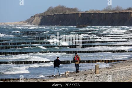 Wustrow, Deutschland. März 2020. Spaziergänger sind auf der Halbinsel Fischland an der turbulenten Ostsee. Sonne und Squalls bis zu Force Eight sorgen für eine beeindruckende Kulisse. Credit: Bernd Wüstneck / dpa-Zentralbild / dpa / Alamy Live News Stockfoto