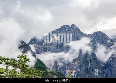 Der Schnee-Berg Jade Dragon, Yulong Xueshan, durchbricht Wolken und Nebel in Lijiang, Provinz Yunnan, China. Die Gletscher sind das ganze Jahr über zu sehen. Stockfoto