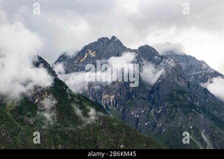 Der Schnee-Berg Jade Dragon, Yulong Xueshan, durchbricht Wolken und Nebel in Lijiang, Provinz Yunnan, China. Die Gletscher sind das ganze Jahr über zu sehen. Stockfoto