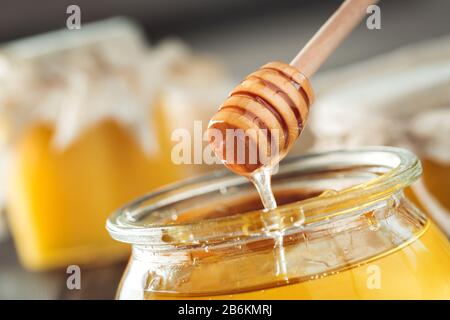 Honighintergrund. Süßer Honig im Glasbecher auf Holzgrund. Stockfoto