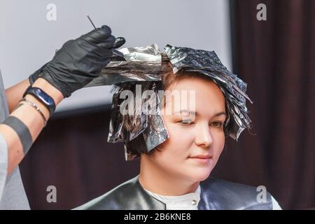 Friseursalon färbt Klientinnen Haare im Friseur Studio Salon, mit Pinsel und Folie, professioneller Farbstoff und Behandlungskonzept Stockfoto