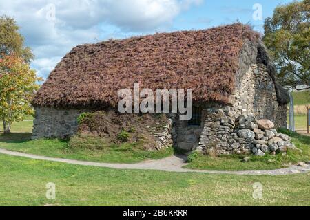 Old Leanach Cottage - ein typisches Haus mit Heideweiher und Reetdachgedecktem Hochland im Culloden Moor, Schottland Stockfoto