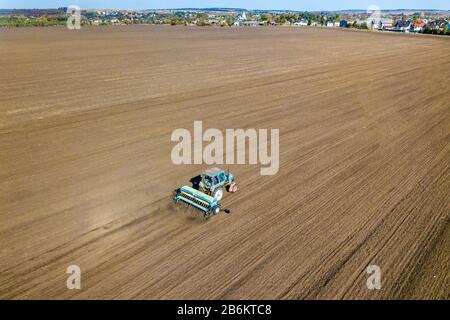 Luftbild eines Traktors, der nach der Ernte im Herbst den schwarzen landwirtschaftlichen Feldplatz pflügt. Stockfoto