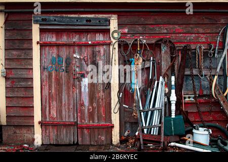 Ein verwitterter und verfallender Arbeitsschack auf den Docks im Hafen von Gloucester steht mit maroden Holzschindeln und einer Fülle von Teilen, Seilen und Vintage Stockfoto