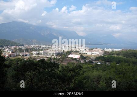 Blick vom beobachtenden Ort zum Tal mit Kemer Stadt in der Region Antalya umgeben von hohen Bergen und ruhigem blauem Mittelmeer in heller Sonne Stockfoto