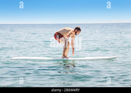 Ein Mann lernt, auf dem offenen Meer mit einem Wasserbrett zu fahren Stockfoto